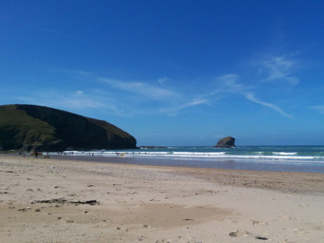 Portreath Beach with a blue sky, breaking waves and gull rock in the distance