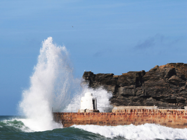 Waves crashing up over the Monkey Hut at the end of Portreath Harbour wall